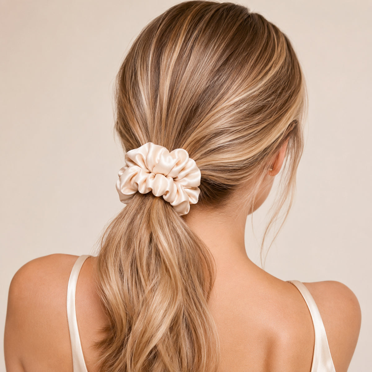 Low ponytail held by a large cream Silk Scrunchie, back view